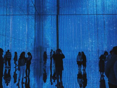 A Group Of People Standing In Front Of A Blue Wall