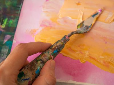 A Person Holding A Paintbrush In Front Of A Painting