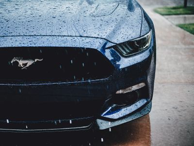 The Front Of A Blue Mustang Parked On The Side Of The Road