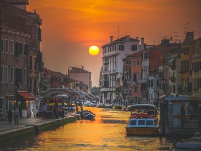 Golden Hour Photography Of City Near Body Of Water With Boat