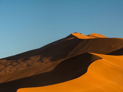 A Group Of Sand Dunes With A Blue Sky In The Background
