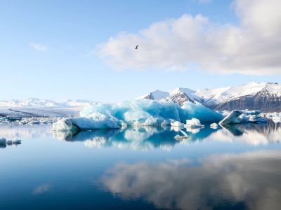Ice Bergs And Alp Mountains Facing Calm Body Of Water