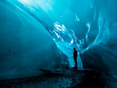 Person Standing In Ice Cave At Daytime