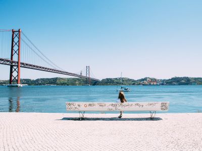 Woman Sitting On White Bench In Front Of Sea